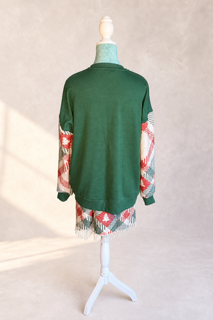 Back view of The Noel Rework showing the forest green sweatshirt body, woven textile sleeves, and fringed lower panel